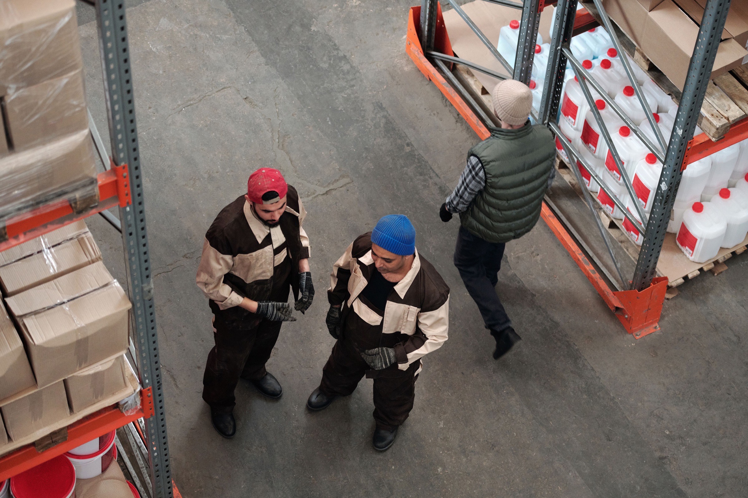 Warehouse staff discussing stock beside commercial shelving